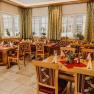 Cozy restaurant with wooden furniture, decorated tables and plants by the window.