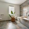 Modern bathroom with bathtub, plant and window.