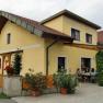 Yellow house with terrace and people sitting outside.