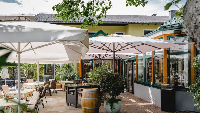 Outdoor area of a restaurant with tables, chairs and parasols.