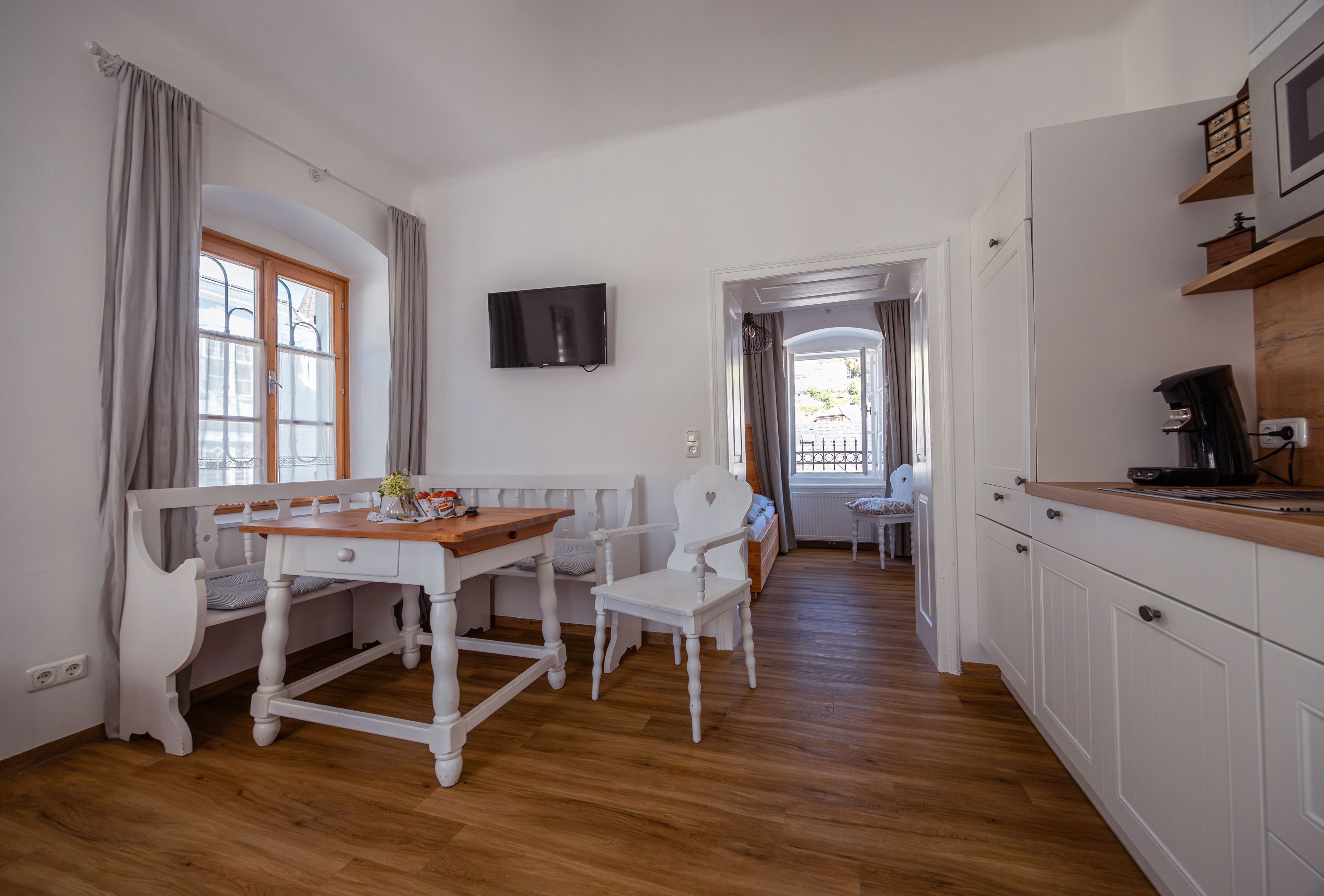 Bright, cozy room with wooden floor, dining table, chairs and kitchenette.