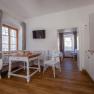 Bright, cozy room with wooden floor, dining table, chairs and kitchenette.