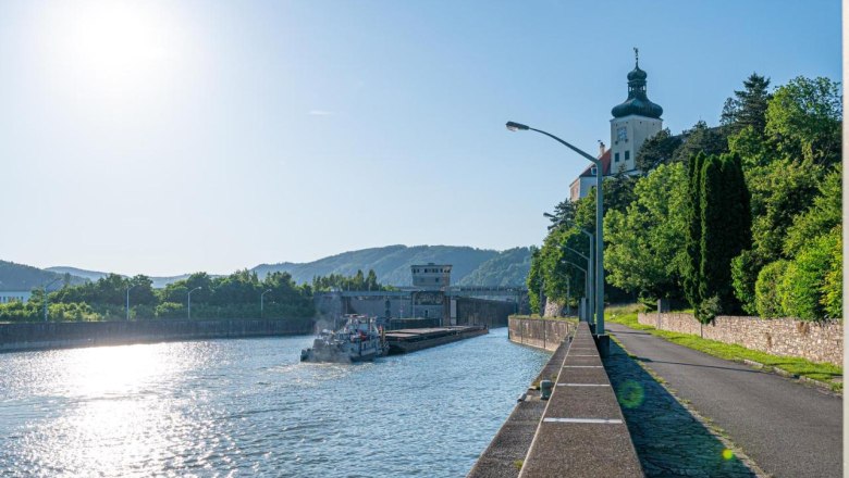 River with ship and building on the bank, sunny sky.
