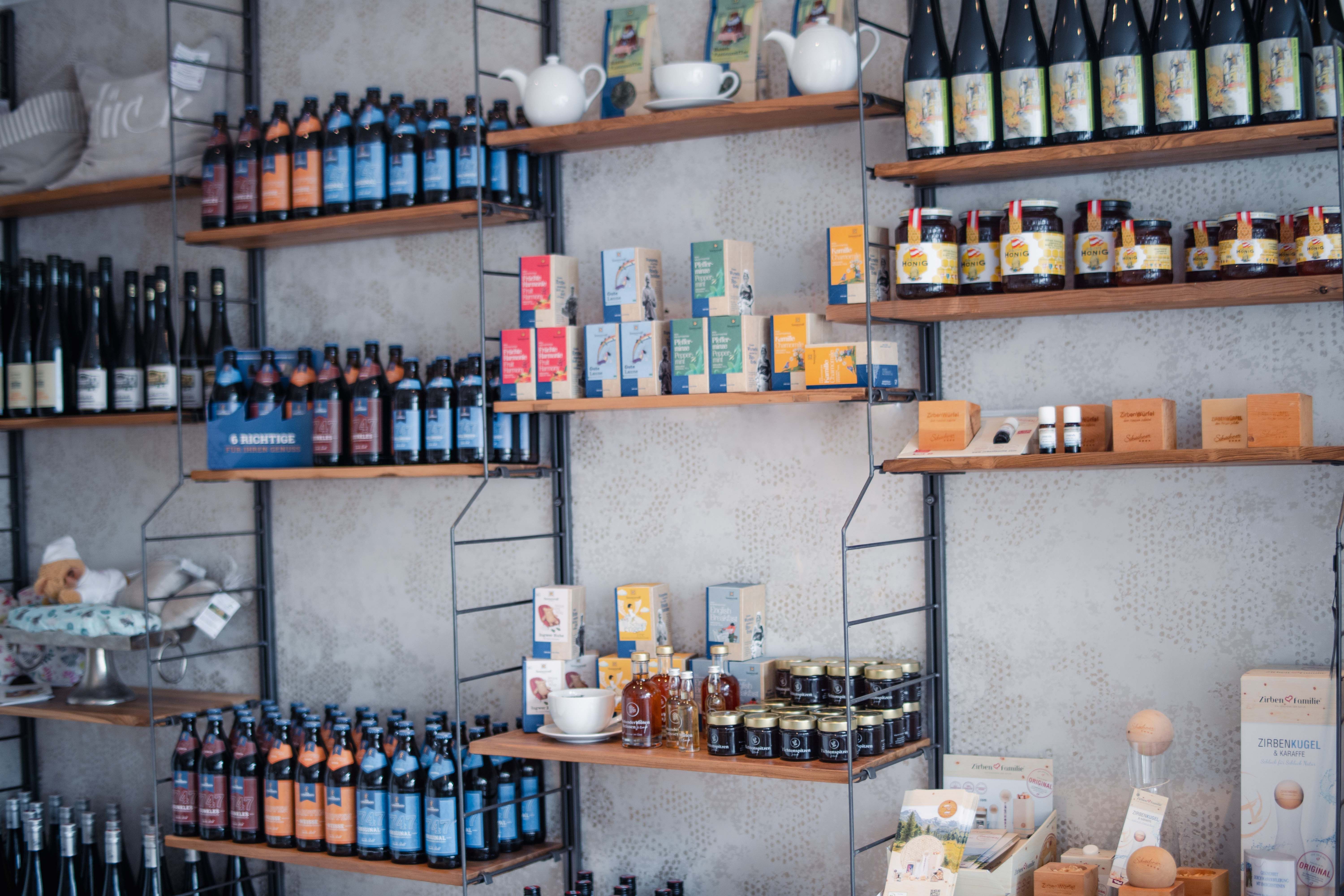 Shelves with various products such as bottles, tea packs and honey jars in a store.