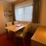 A cozy room with wooden furniture, table, chairs and a window with curtains.