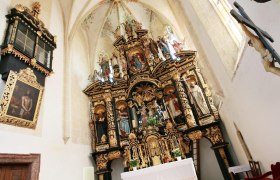 Interior view of the Annaberg pilgrimage church with its richly decorated altar and religious statues.
