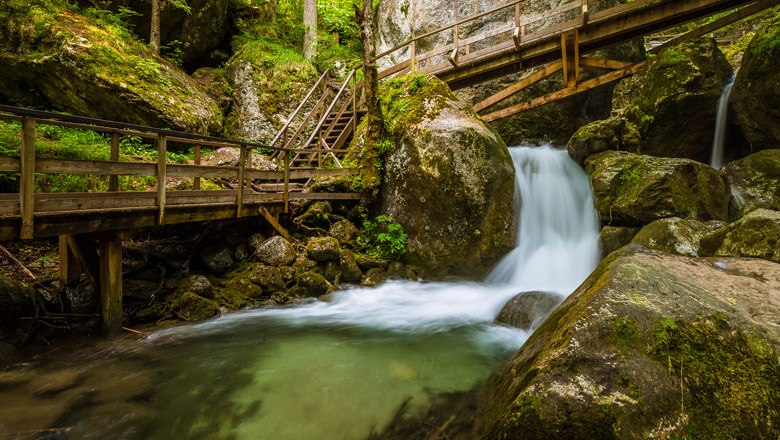 Wooden bridges and waterfall in a wooded gorge.