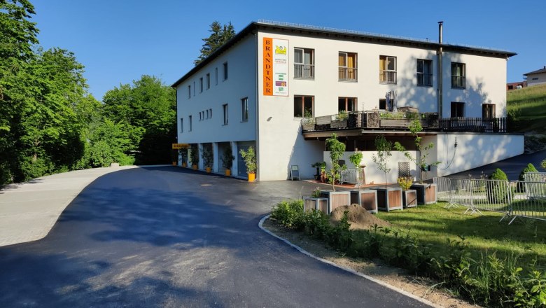 Building with the inscription 'Brandtner', surrounded by trees and a parking lot.