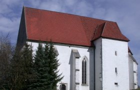 St. Andrew's Church in Kirchberg an der Pielach with a red tiled roof and white fa&ccedil;ade, surrounded by trees and a path in the foreground.