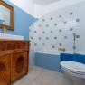 A bathroom with blue walls, a bathtub, a washbasin on a wooden cabinet and a golden mirror.