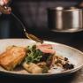 A plate of veal medallions, asparagus and puff pastry, garnished with sauce and herbs.