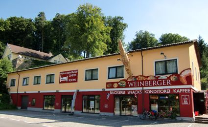 Exterior view of a bakery with yellow facade and red sign.