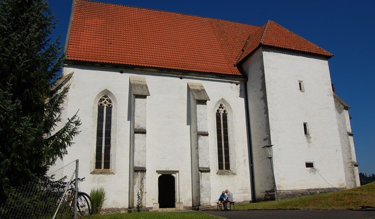 White church with a red roof and Gothic windows, blue sky.