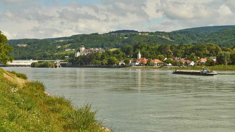River landscape with village and hills in the background.