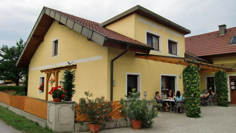Yellow house with terrace and people sitting outside.