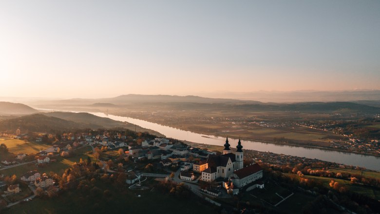 Aerial view of a church at sunset, surrounded by river and landscape.