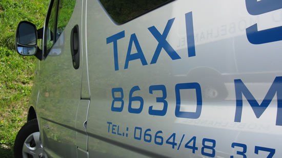 Close-up of a silver cab with blue lettering and telephone number.