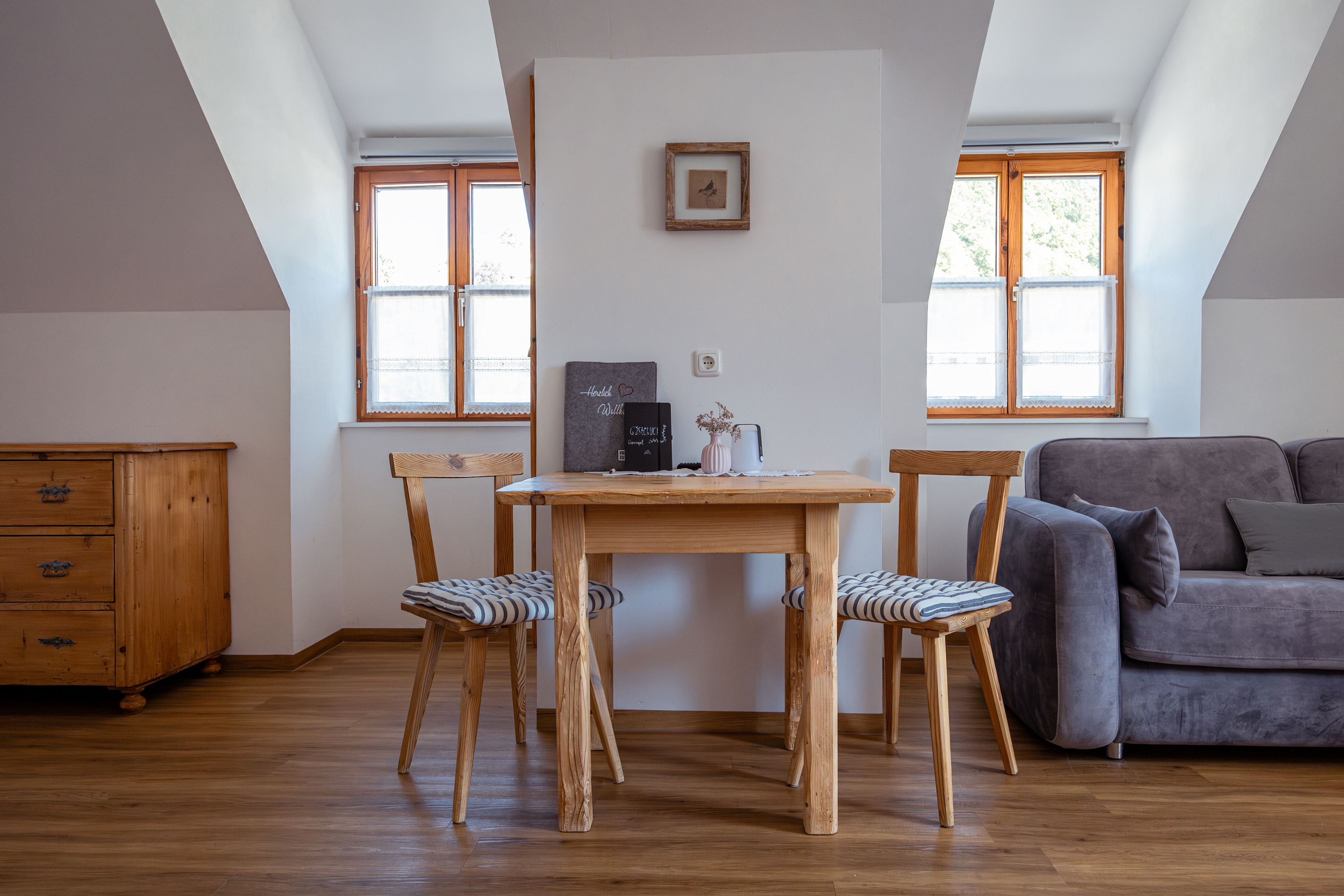 Cozy living area with wooden table, two chairs and sofa.