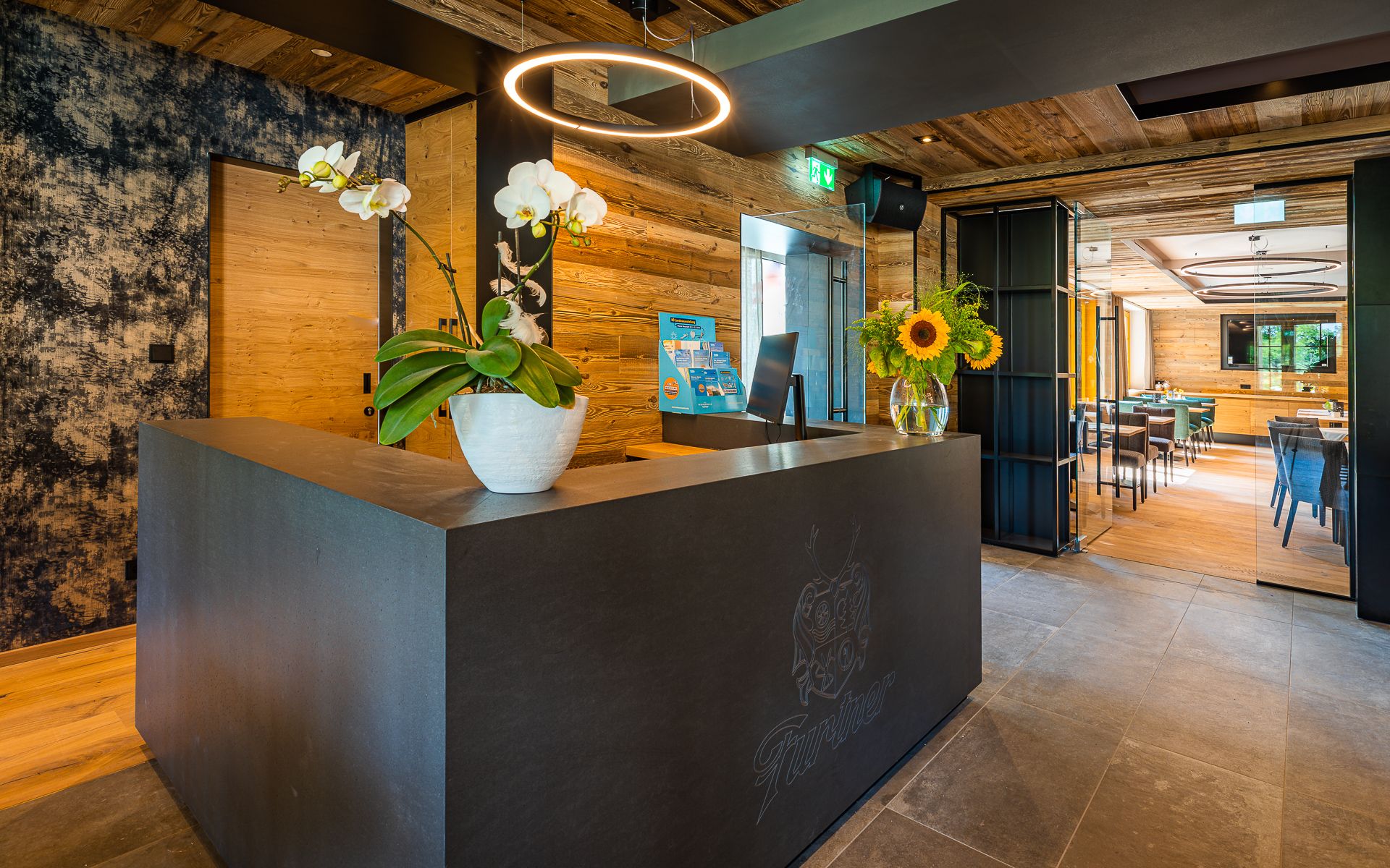 Modern reception with wood paneling, orchids and sunflowers on the counter.