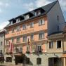 Facade of the Hotel zum Kirchenwirt with flags and blue sky.