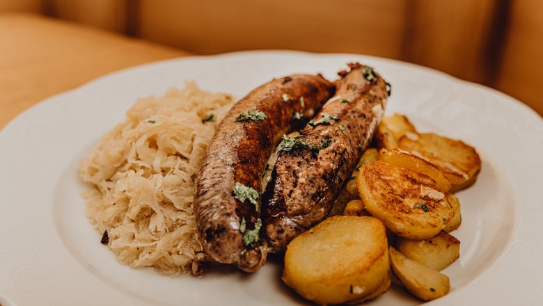 A plate of liver sausage, roast potatoes and sauerkraut.