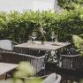 A cozy guest garden with covered tables and a green hedge in the background.
