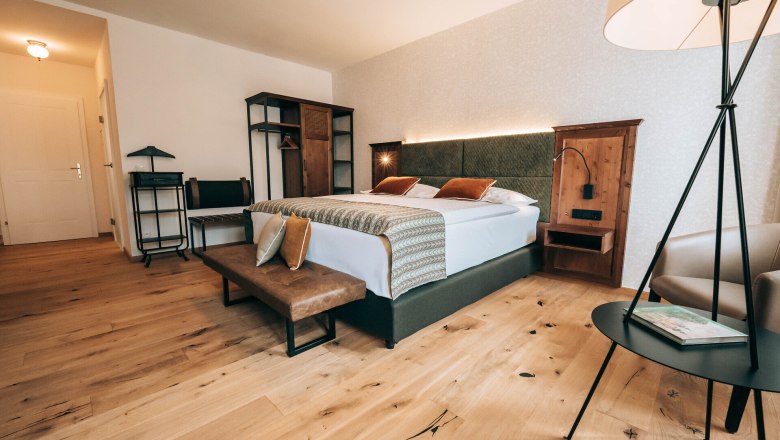 Modern hotel room with double bed, wooden floor and stylish furniture.