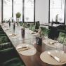 Elegant restaurant with green chairs and table setting.