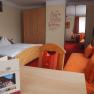 A cozy hotel room with a double bed, a sofa, a table and a wardrobe. There is a motivational slogan on the wall.