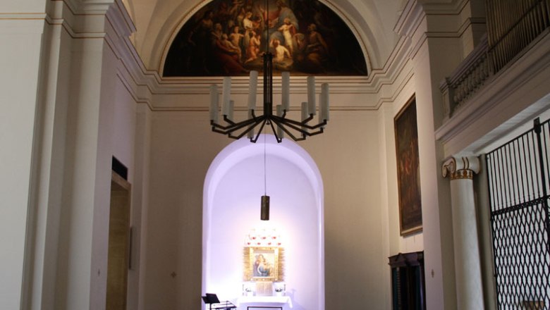Interior view of a church with altar and painting on the wall.