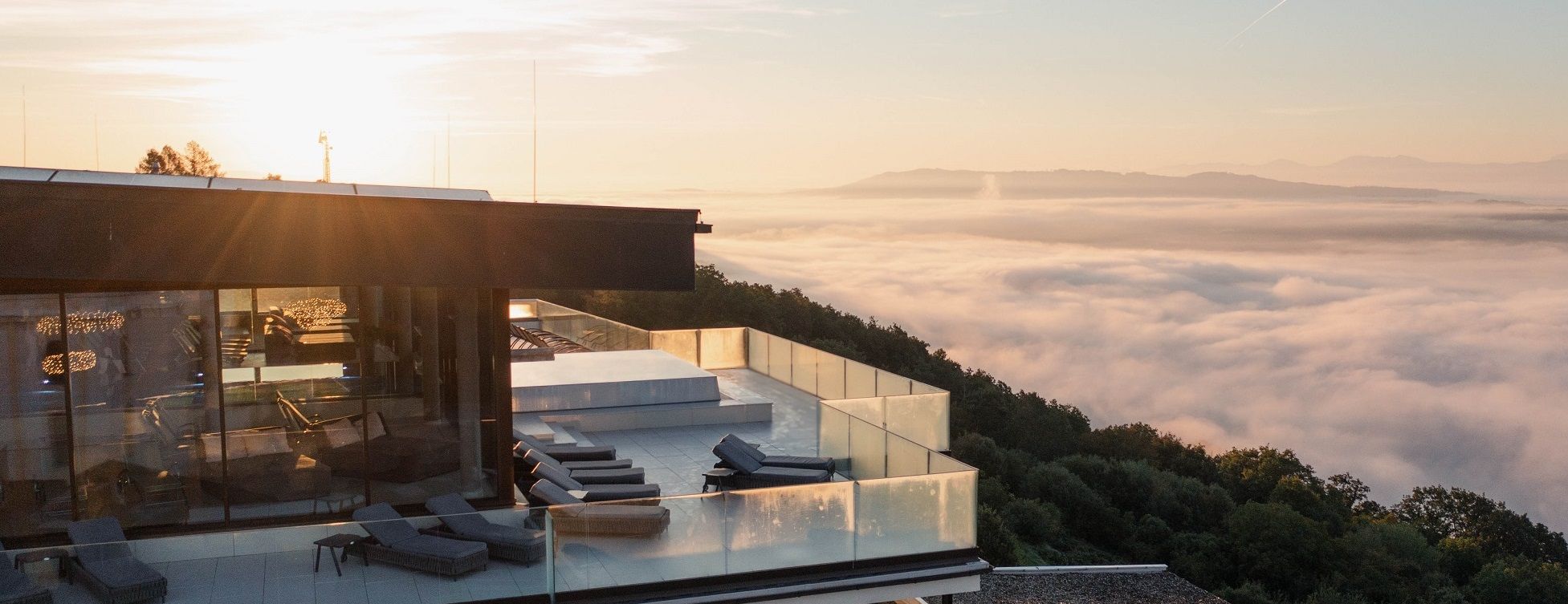 Modern building with terrace above a sea of fog at sunrise.