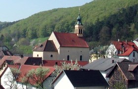 Maria Raisenmarkt pilgrimage church in a rural setting with hills in the background.