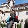 Two people with rucksacks and hiking poles stand in front of Lilienfeld Abbey and look up.