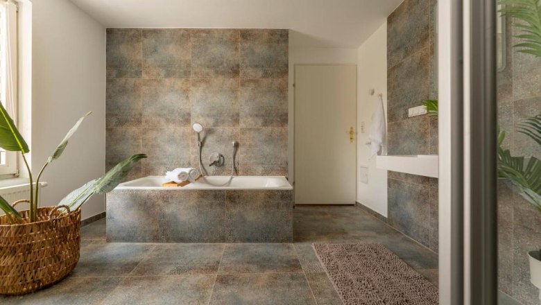 Modern bathroom with bathtub, plants and towel.