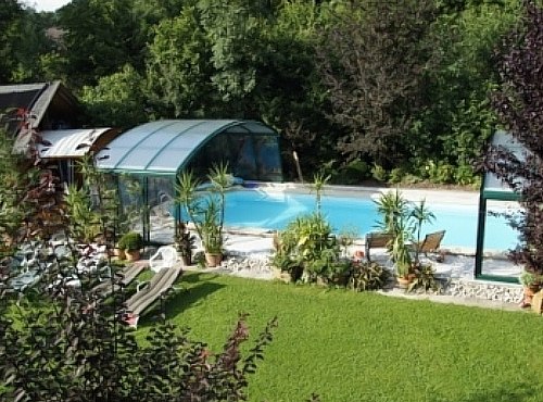 Pension Landhaus Ingrid, © Pension Landhaus Ingrid A covered outdoor pool with sun loungers and plants, surrounded by greenery.
