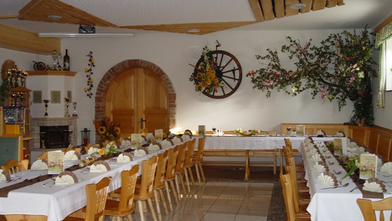 A festively decorated dining room with long tables, decorated with flowers and napkins, in a rustic ambience.