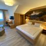 Modern hotel room with double bed, desk, TV and large mural.