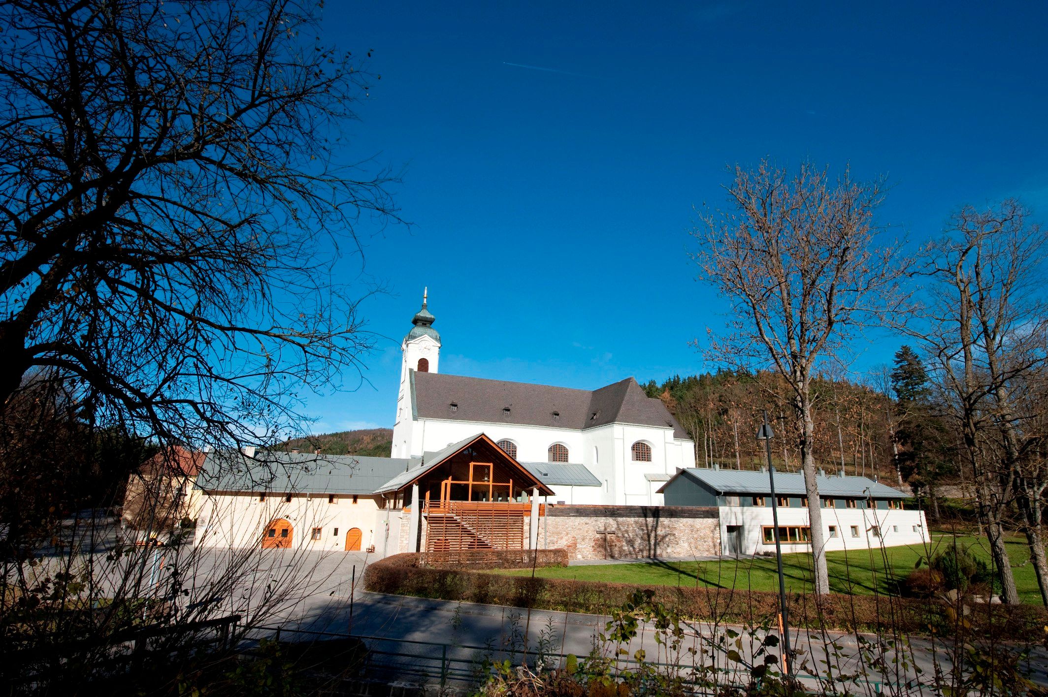 Pilgrimage church Klein-Mariazell with blue sky and trees in the foreground.