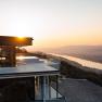 Modern building with glass façade at sunset, view of river and landscape.