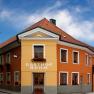 A traditional inn with an orange and yellow façade and red roof tiles under a blue sky.