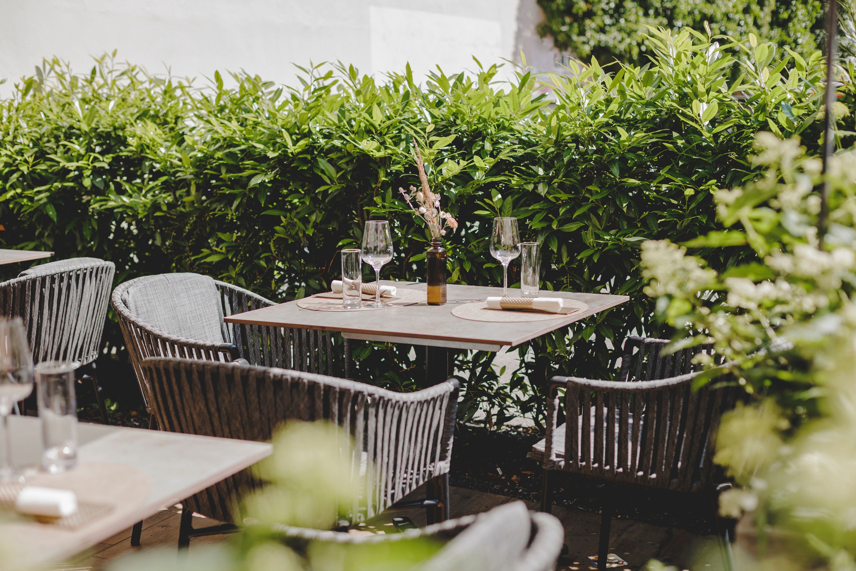 A cozy guest garden with covered tables and a green hedge in the background.