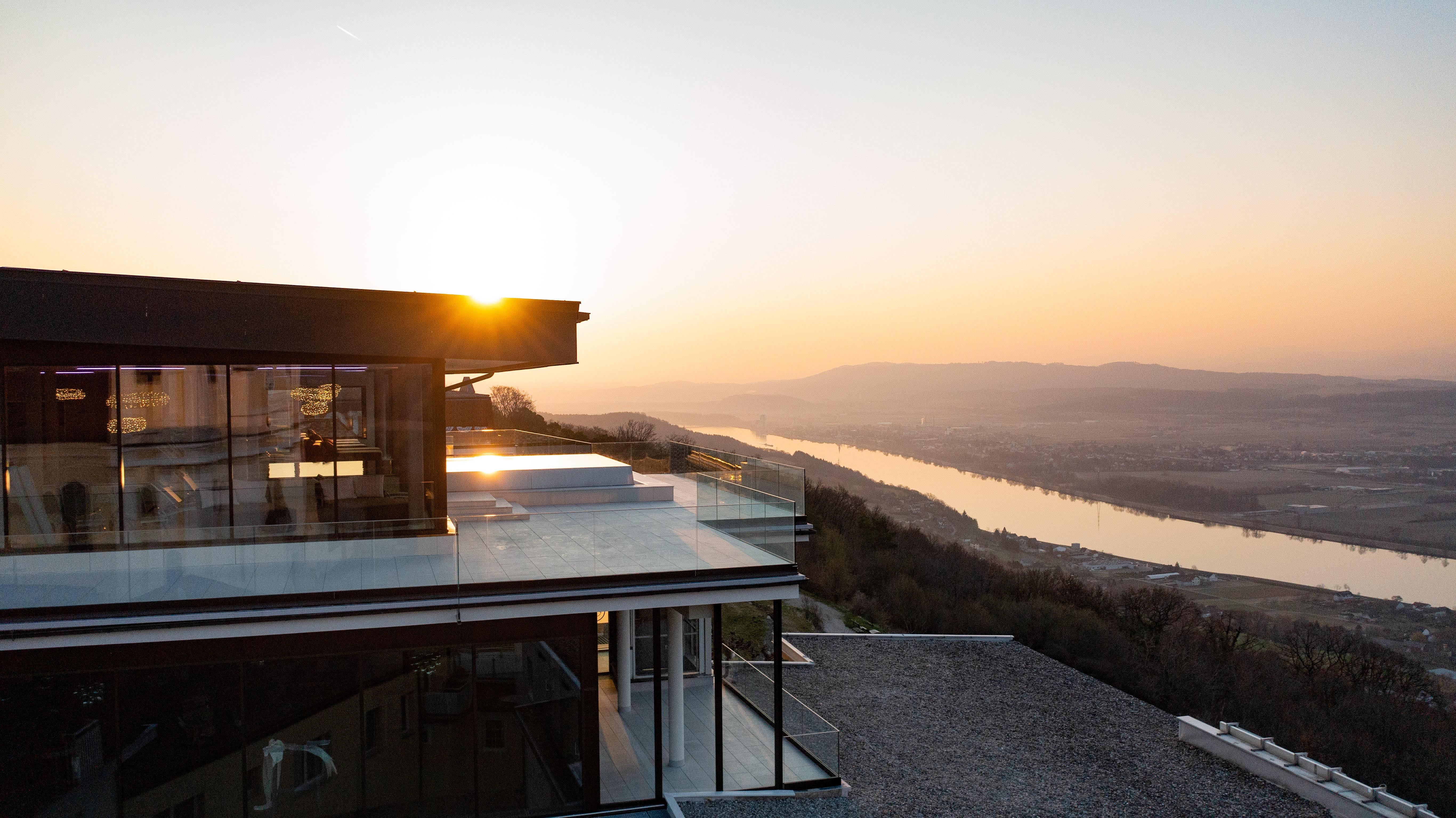 Infinity pool at Hotel Schachner with a view of the river landscape at sunset.